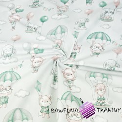 Cotton cuddly toys with pink-green parachutes on a light gray background